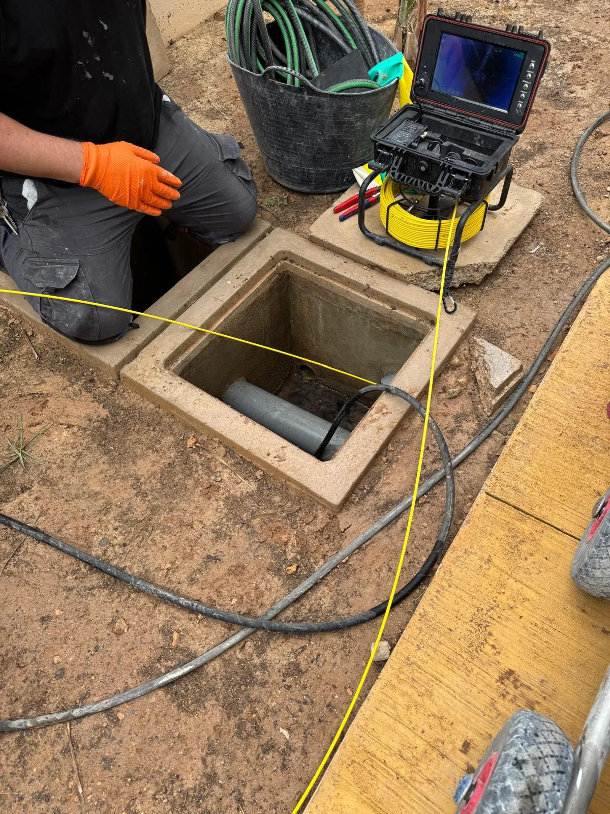 Cámara de inspección entrando en la tubería de una arqueta, con el monitor al lado